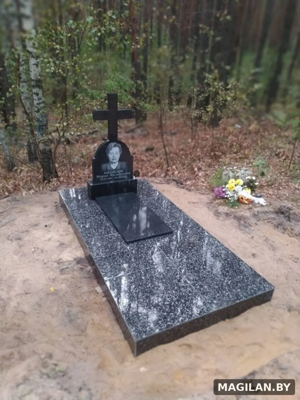 Памятник с крестом и сплошная тёмная плиточная облицовка участка в Речицком районе