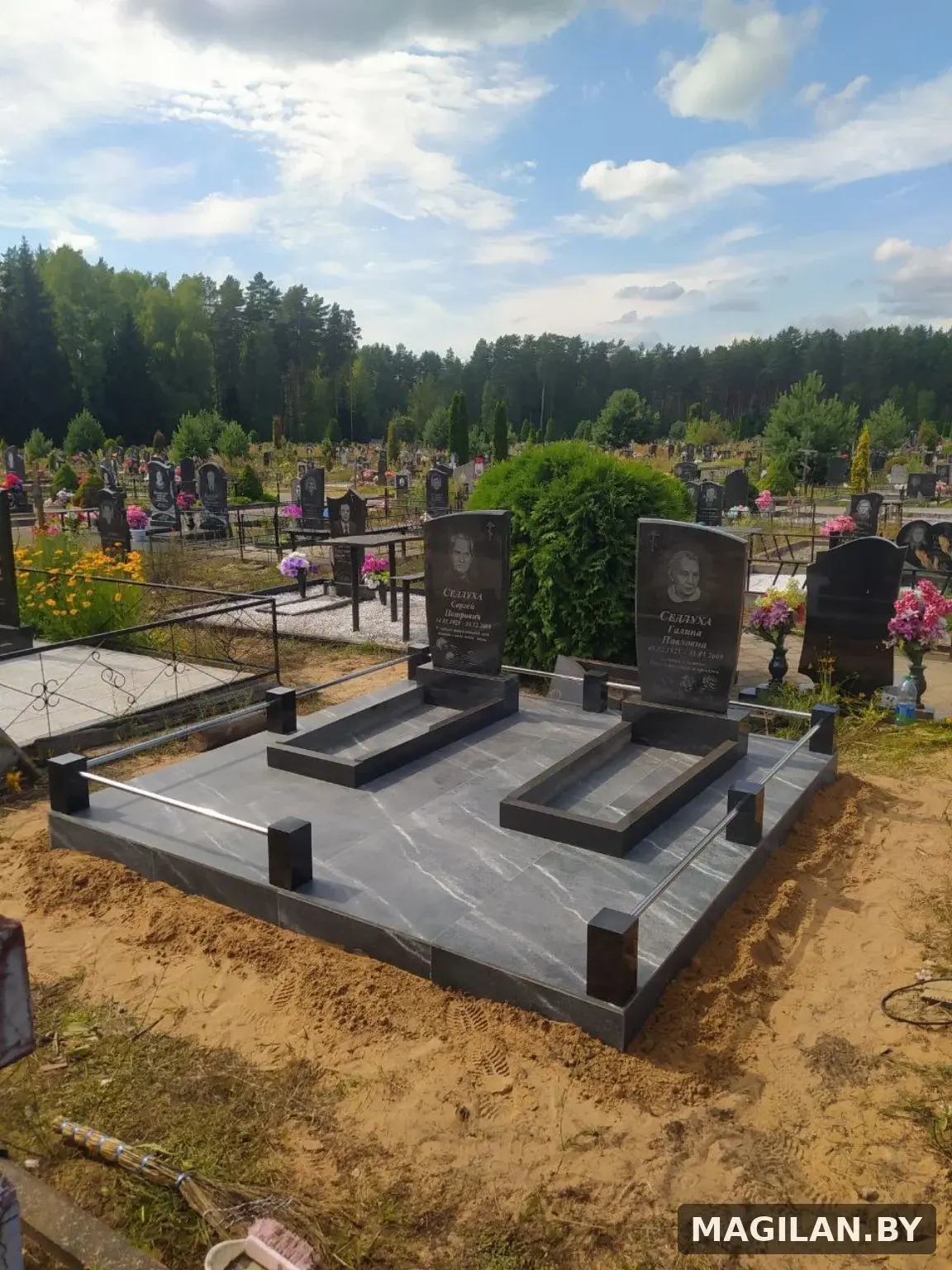 Два памятника на общей тёмной плиточной площадке с металлическими ригелями на городском кладбище Полоцка