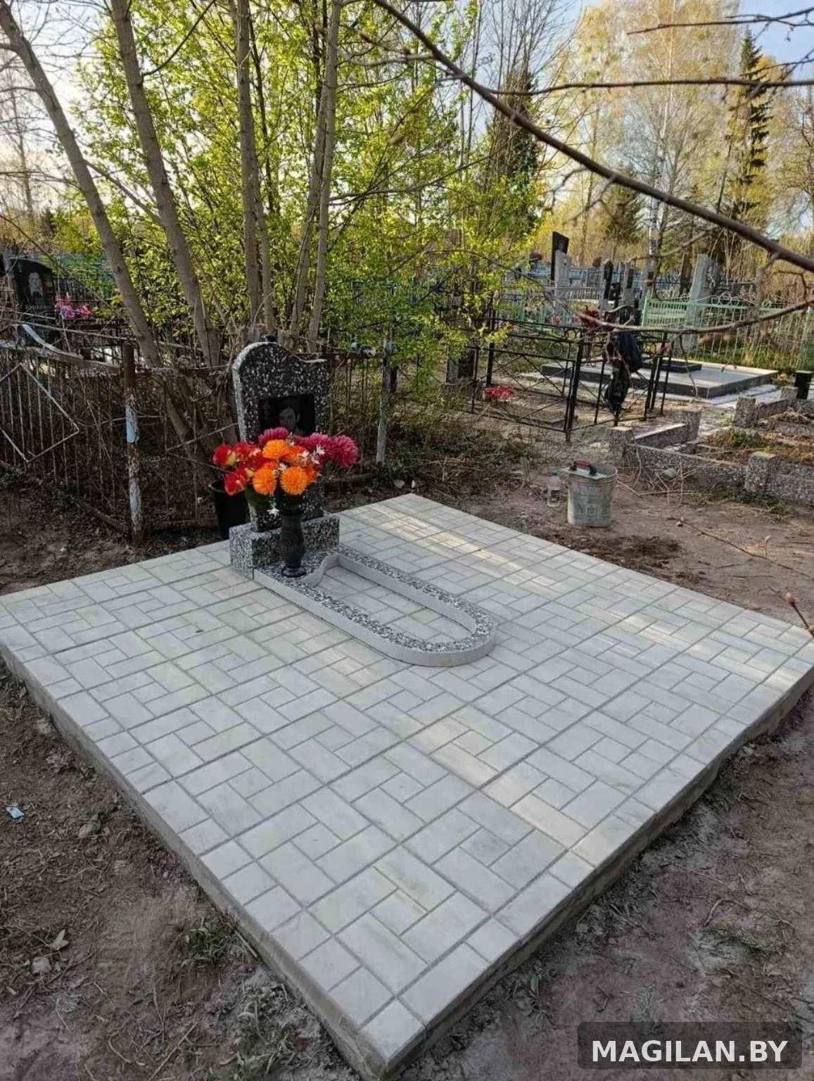 Памятник с цветником и светлым плиточным благоустройством на городском кладбище Калинковичей