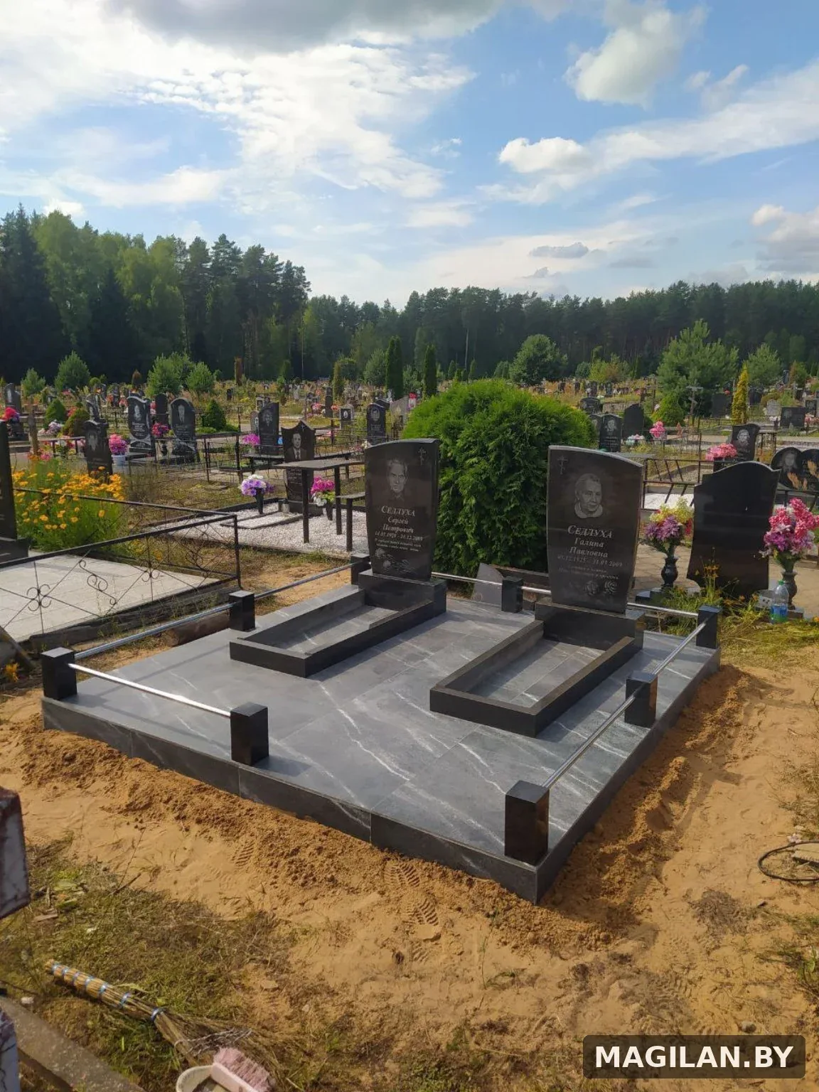 Два памятника на общей тёмной плиточной площадке с металлическими ригелями на городском кладбище Полоцка