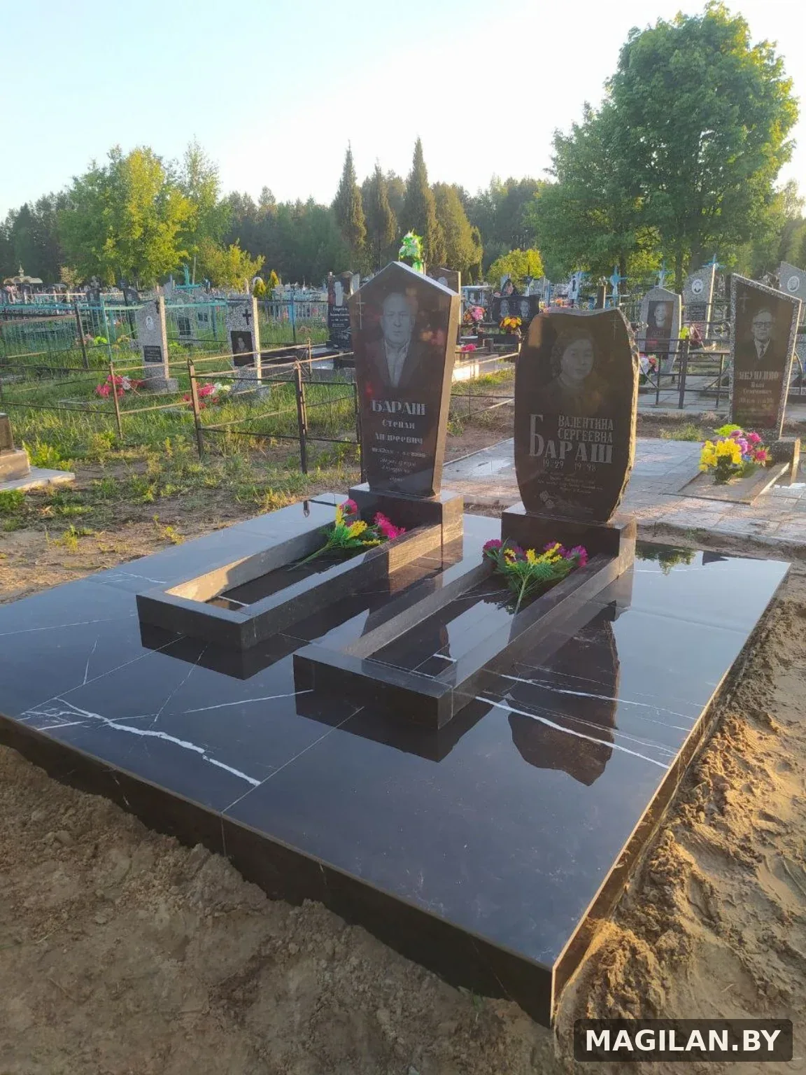 Два памятника с цветниками на общей тёмной плиточной площадке в Калинковичах